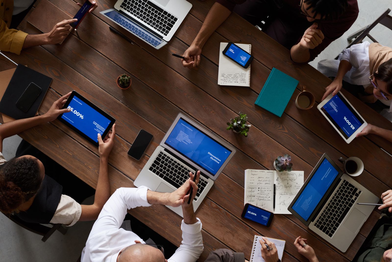 A team reviewing data together around a table, laptops and tablets open.