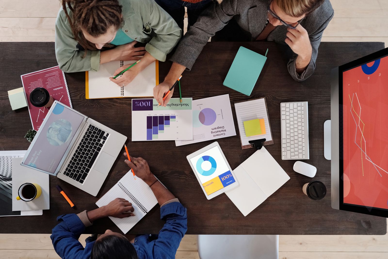 A team working through charts and diagrams together at a table, seen from above.