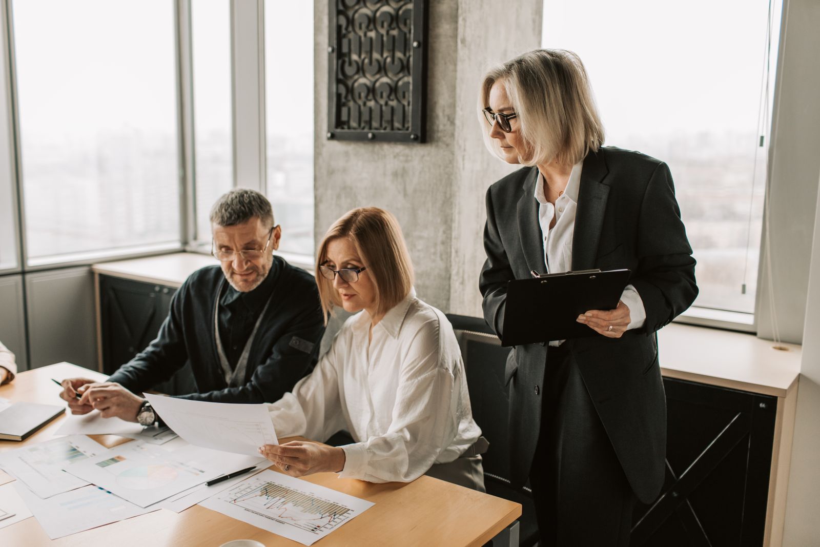 Three experienced professionals reviewing process diagrams and charts together in an office.