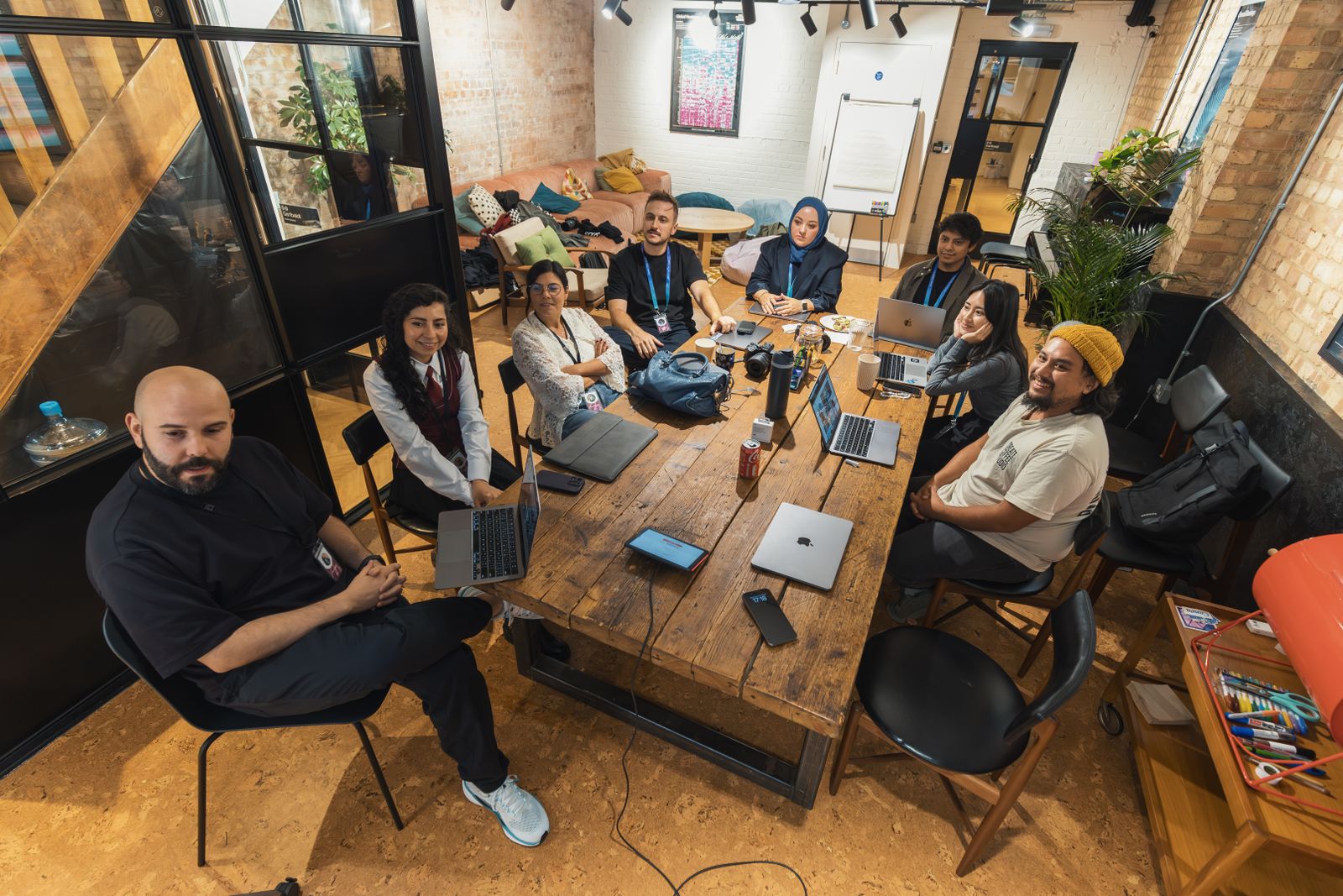 A diverse team gathered around a table, collaborating with laptops and notes.